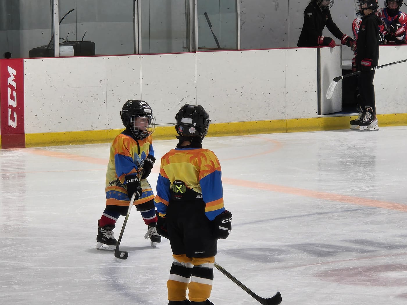 Two young players in custom sunset jerseys talking on the ice