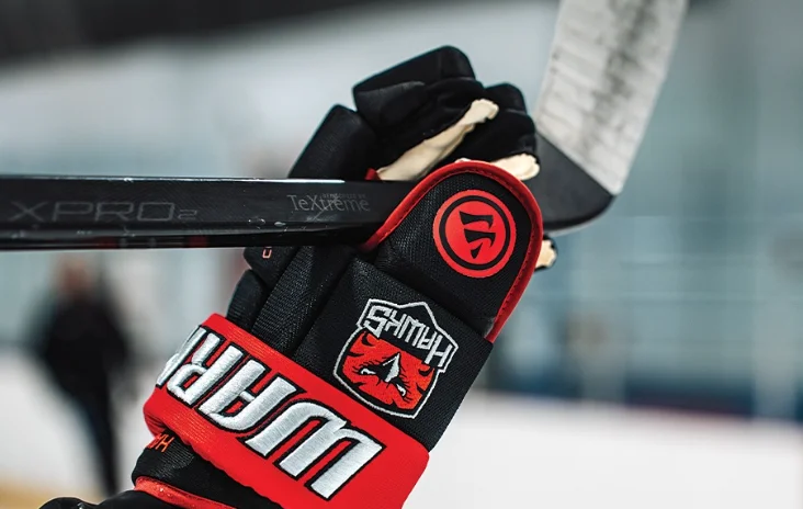 Custom Warrior team glove gripping a hockey stick