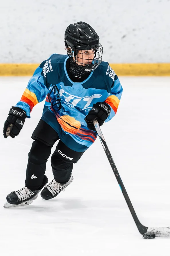 Young player skating in a custom teal camp jersey